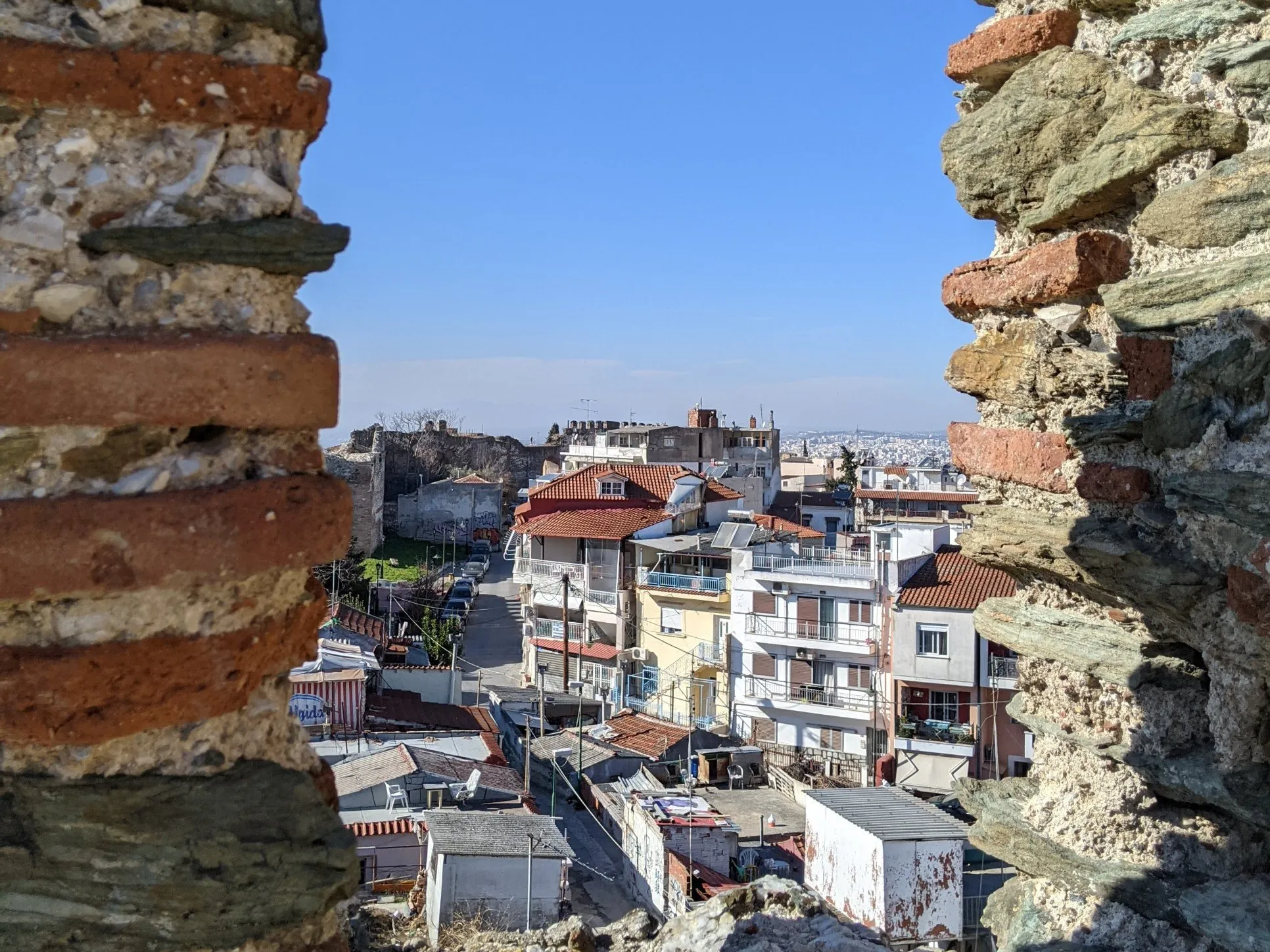 Θέα μέσα από ένα άνοιγμα στα βυζαντινά τείχη προς τα παλιά σπίτια και τα στενά δρομάκια της Άνω Πόλης, Θεσσαλονίκη