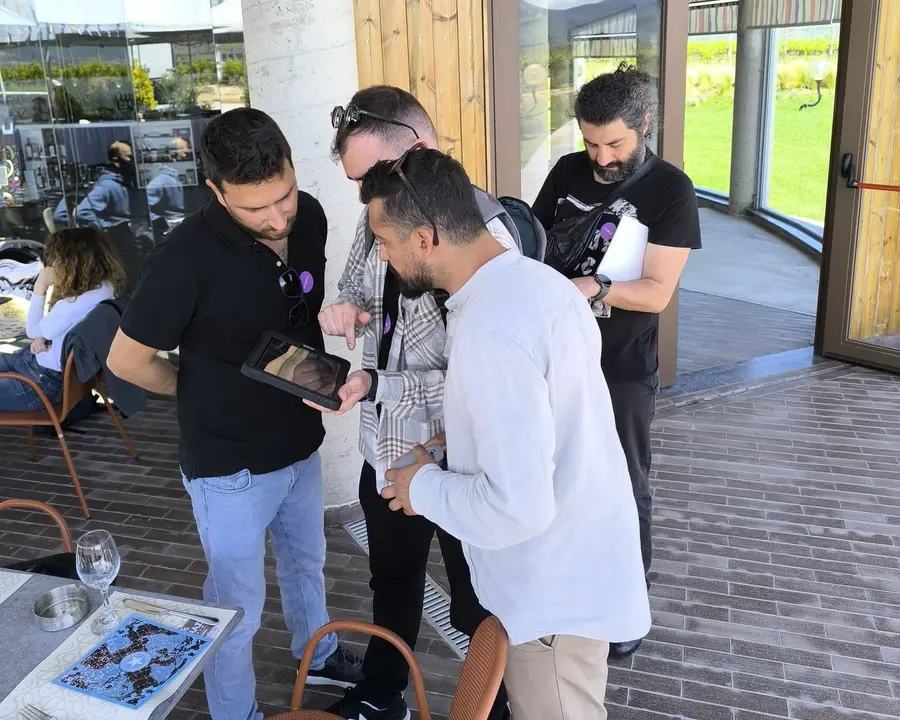 Τέσσερις παίκτες γύρω από ένα tablet στη βεράντα οινοποιείου κατά τη διάρκεια του Black Out, ενός AR escape game της Salty Soil.