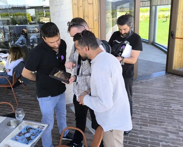 Τέσσερις παίκτες γύρω από ένα tablet στη βεράντα οινοποιείου κατά τη διάρκεια του Black Out, ενός AR escape game της Salty Soil.