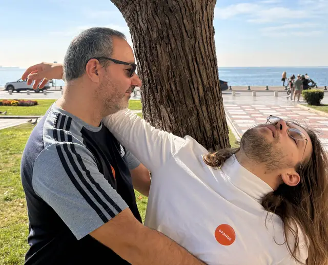 Two colleagues act out a pose against a tree on the Thessaloniki waterfront for a photo challenge during a Salty Soil city treasure hunt