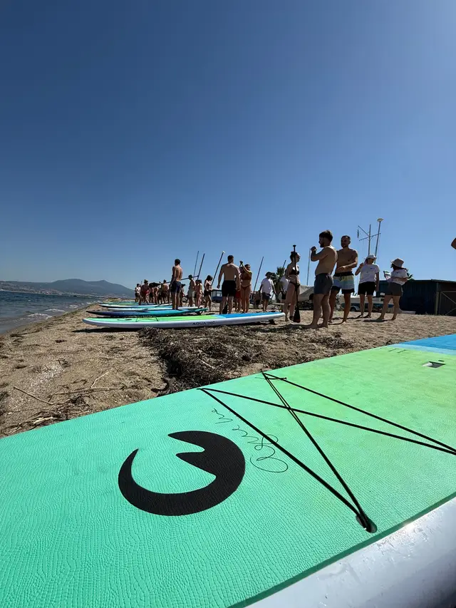Stand-up paddle boards lined up on a beach as a company group gets ready for a SUP session with Salty Soil instructors near Thessaloniki