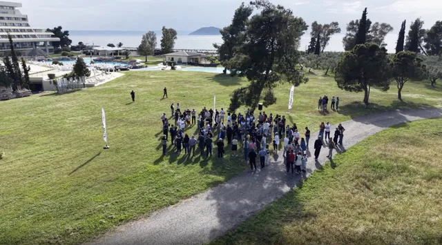 Aerial view of a large company group gathered on a seaside resort lawn in Halkidiki for a team building event run by Salty Soil