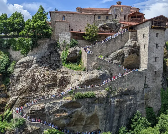 Visitors climb the stone stairs to the Great Meteoron monastery on its rock at Meteora, on a Salty Soil day trip from Thessaloniki