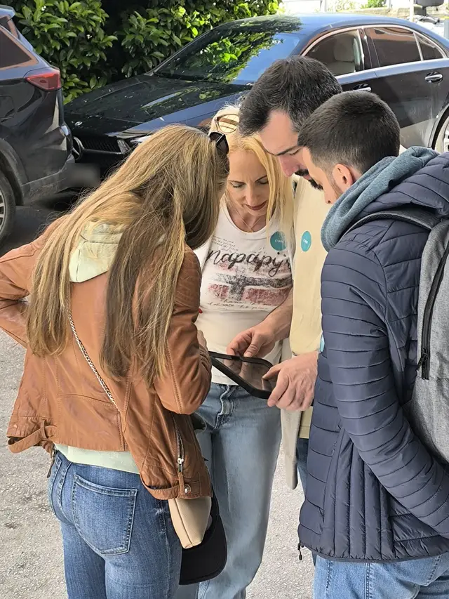 Four players lean in over a tablet to solve a clue during Operation Mindfall, a Salty Soil AR escape game