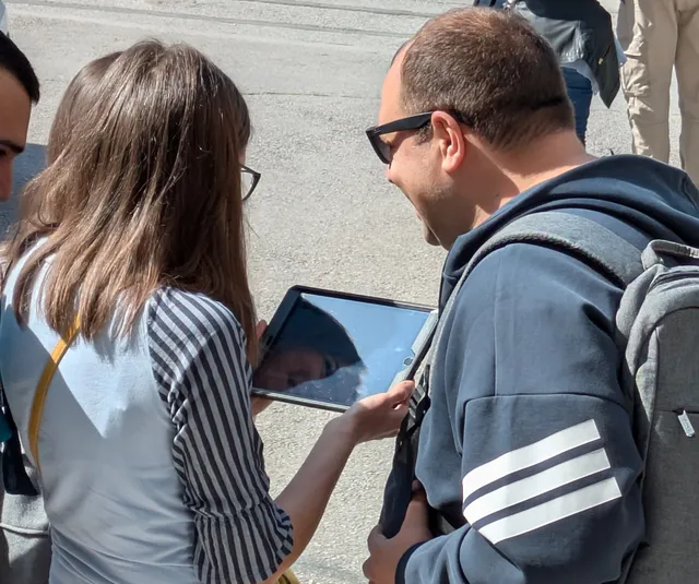 Δύο παίκτες ελέγχουν το επόμενο στοιχείο σε tablet σε δρόμο της Θεσσαλονίκης κατά τη διάρκεια του Operation Mindfall, ενός AR escape game της Salty Soil.