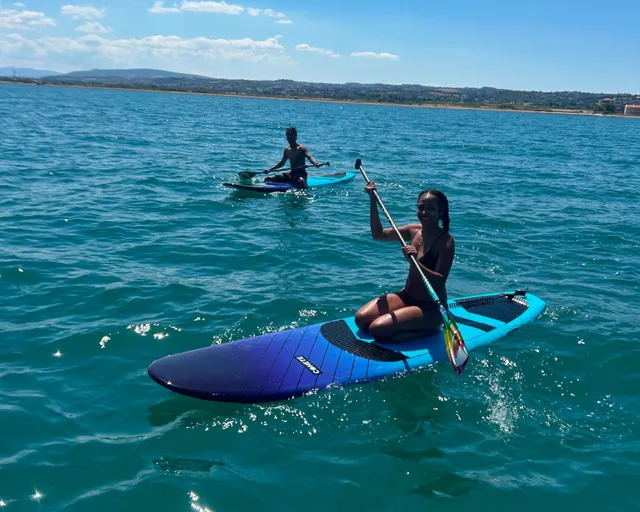 Two guests kneel on stand-up paddleboards on the turquoise water off Perea, near Thessaloniki, on a Salty Soil SUP tour