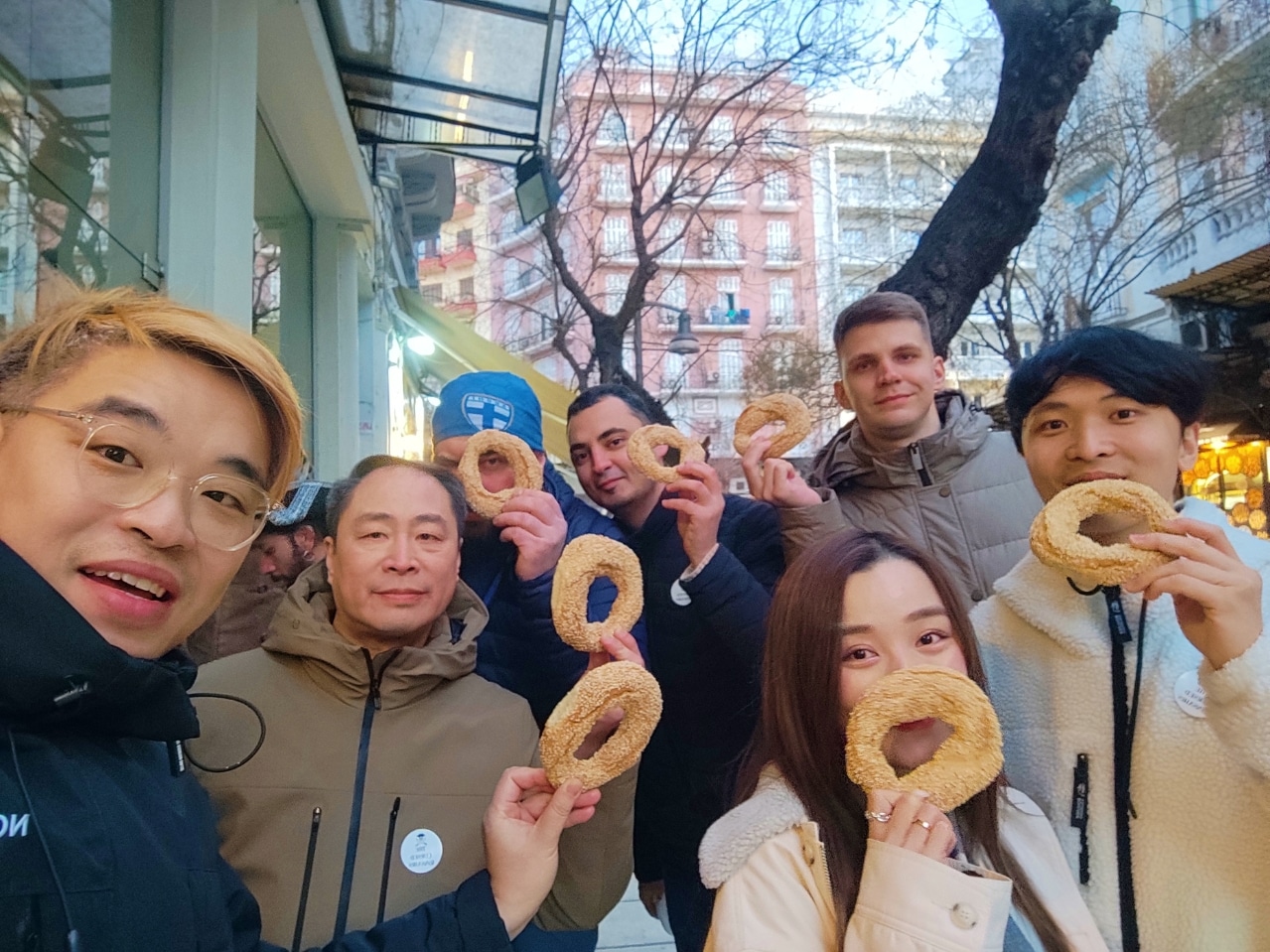 Group of food tour guests holding Thessaloniki koulouri during a street food experience with Salty Soil in Thessaloniki